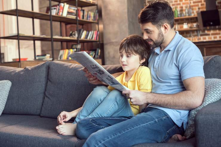 Papà e figlio seduti sul divano leggono le ultime novità - foto Depositphotos - PalermoLive.it